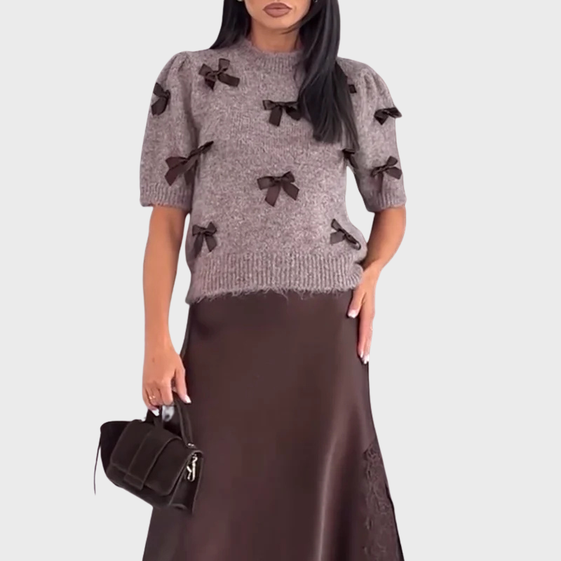 Stickad damsweater med dekorativa rosetter och kort ärm