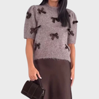 Stickad damsweater med dekorativa rosetter och kort ärm